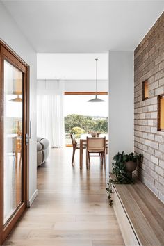 an open living room and dining area with brick wall, wood flooring and large windows