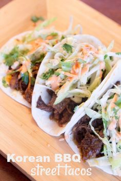 three beef tacos on a cutting board with cole slaw