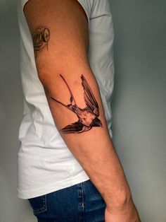 a man's arm with a bird tattoo on the left side of his arm