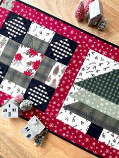 a quilted table topper sitting on top of a wooden table next to some decorations