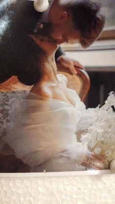 a man and woman are kissing in front of a cake with white frosting on it