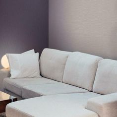 a white couch sitting next to a table with a lamp on it's side