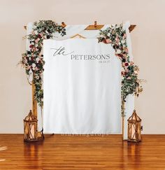 a white backdrop with flowers and candles on the floor for a wedding ceremony at the pettersons