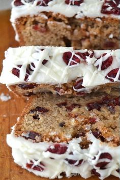 three slices of cake with white frosting and cranberries sitting on a cutting board