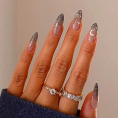 a woman's hand with silver and white nail polish on her nails, holding a ring