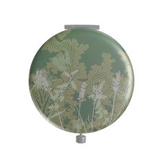 a round mirror with green and white floral designs on it's sides, hanging from a metal rod