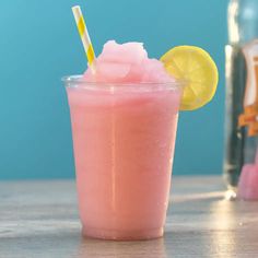 a pink drink with a yellow and white striped straw sitting on top of a wooden table