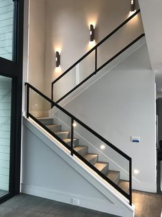 an empty room with some stairs and lights on the wall next to it's glass door