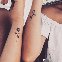 two women with matching tattoos on their arms sitting next to each other and one has a rose tattoo on her arm