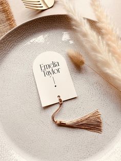 a plate with a place card on it and some feathers next to the table setting