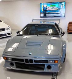 a car is parked in a showroom with other cars on the wall behind it