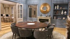 a dining room with blue walls and chairs around a round table in front of a fireplace