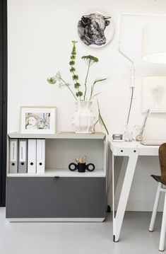 a white desk with some plants and pictures on the wall