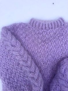 a close up of a purple knitted sweater on a white surface with the top stitched off