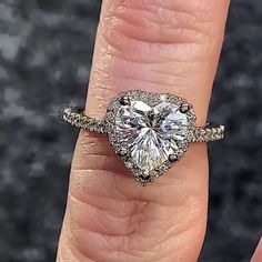 a woman's engagement ring with a heart shaped diamond in the center and pave band