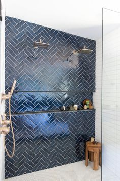 a bathroom with blue tiled walls and white flooring, along with a walk in shower