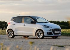 a white car parked on the side of a road near some grass and trees in the background