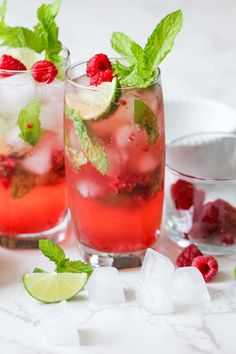 two glasses filled with raspberry mojitas and mint garnishes