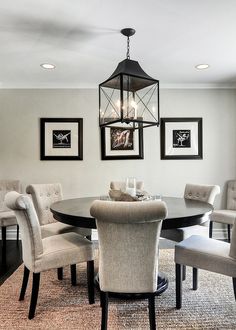 a dinning room table with chairs and pictures on the wall above it, along with two chandeliers