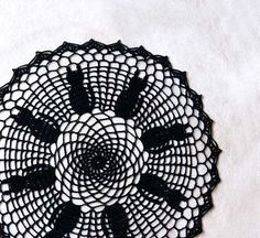 a black doily is shown on a white surface with an intricate design in the center