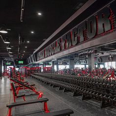 a gym with rows of exercise equipment and red lettering on the wall that says club