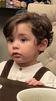 a little boy sitting in a high chair looking at the camera