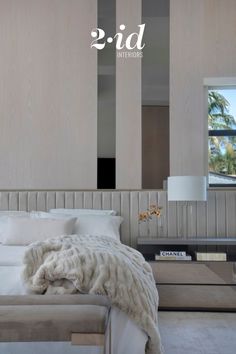 a white bed sitting in a bedroom next to a window with palm trees on it