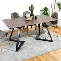 a dining table with chairs around it on a rug in front of a white wall