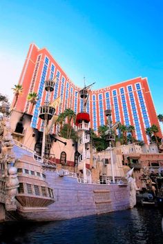 a boat is docked in front of a hotel with palm trees on the top and bottom