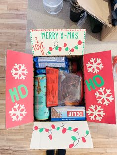 an open christmas gift box on the floor with candy and other items in it that are labeled merry x - mas