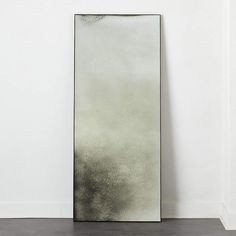 a mirror sitting on top of a wooden floor next to a white wall in an empty room