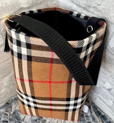 a brown and black plaid bag sitting on top of a stone floor next to a wall