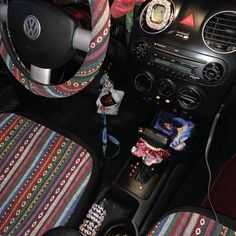 the interior of a car is decorated with colorful fabric and decorative accessories, including a steering wheel cover