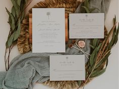 the wedding stationery is laid out with greenery