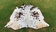 a brown and white spotted cowhide rug on green grass