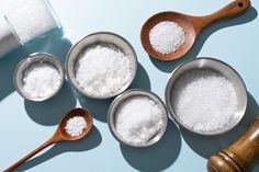 four spoons with sugar in them next to salt and pepper shakers on a blue surface