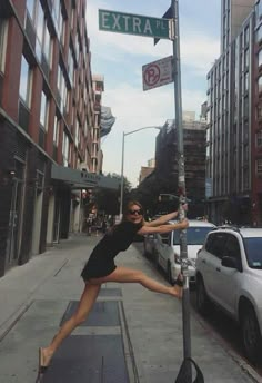 a woman leaning up against a street sign