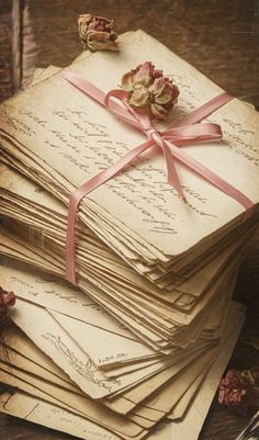 a stack of old fashioned envelopes wrapped in pink ribbon