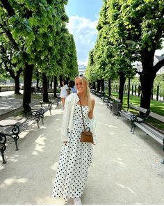 a woman in a polka dot dress is walking down the street with her hand on her hip