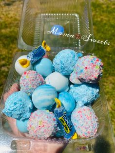 a person holding a plastic container filled with blue and white frosted donut holes