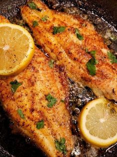 two pieces of fish in a pan with lemons and parsley