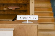 there is a sign that says information on the front of a wooden desk with stairs in the background