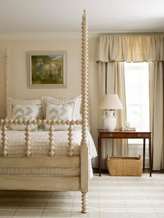 a white bed sitting in a bedroom next to a window with drapes on it