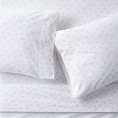 a bed with white sheets and polka dot print on it's pillowcases