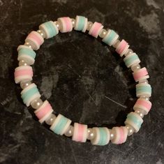 a close up of a bracelet with beads on a table in front of a black surface