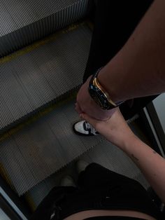 a woman is walking down an escalator with her hand on the floor next to another person's leg