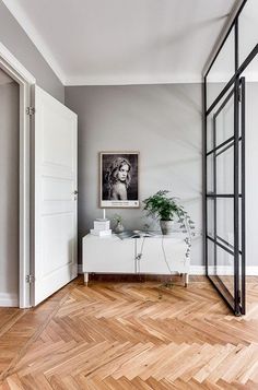 a living room with wood flooring and white furniture in the corner, along with a painting on the wall