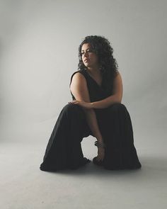 a woman sitting on the ground in a black dress