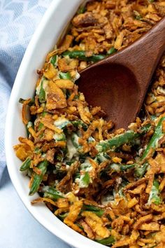 a wooden spoon is in a casserole dish filled with green beans and fried onions