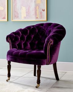 a purple chair sitting on top of a white rug next to a blue wall and paintings